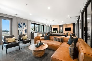 A modern living room with a large brown leather couch and a wooden coffee table.